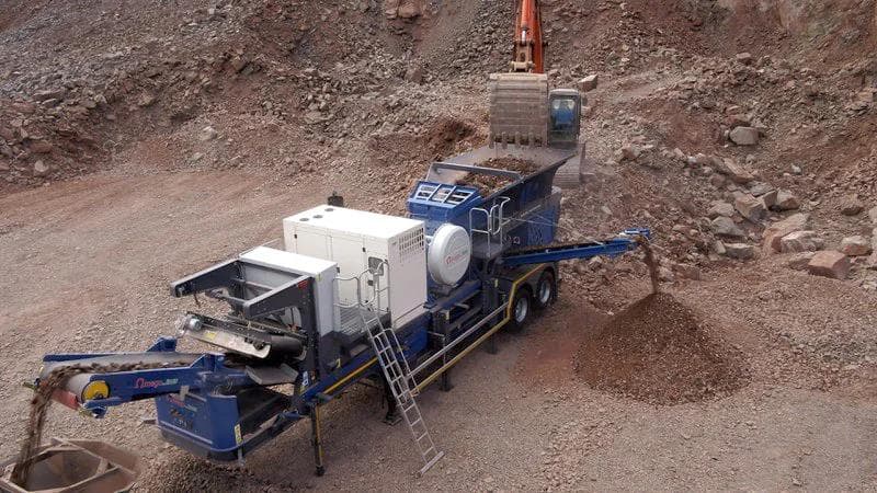 excavator loading the hopper of a blue omega jaw crusher on site