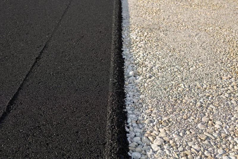 New paved road edge and curb. The texture of new asphalt and crushed stone