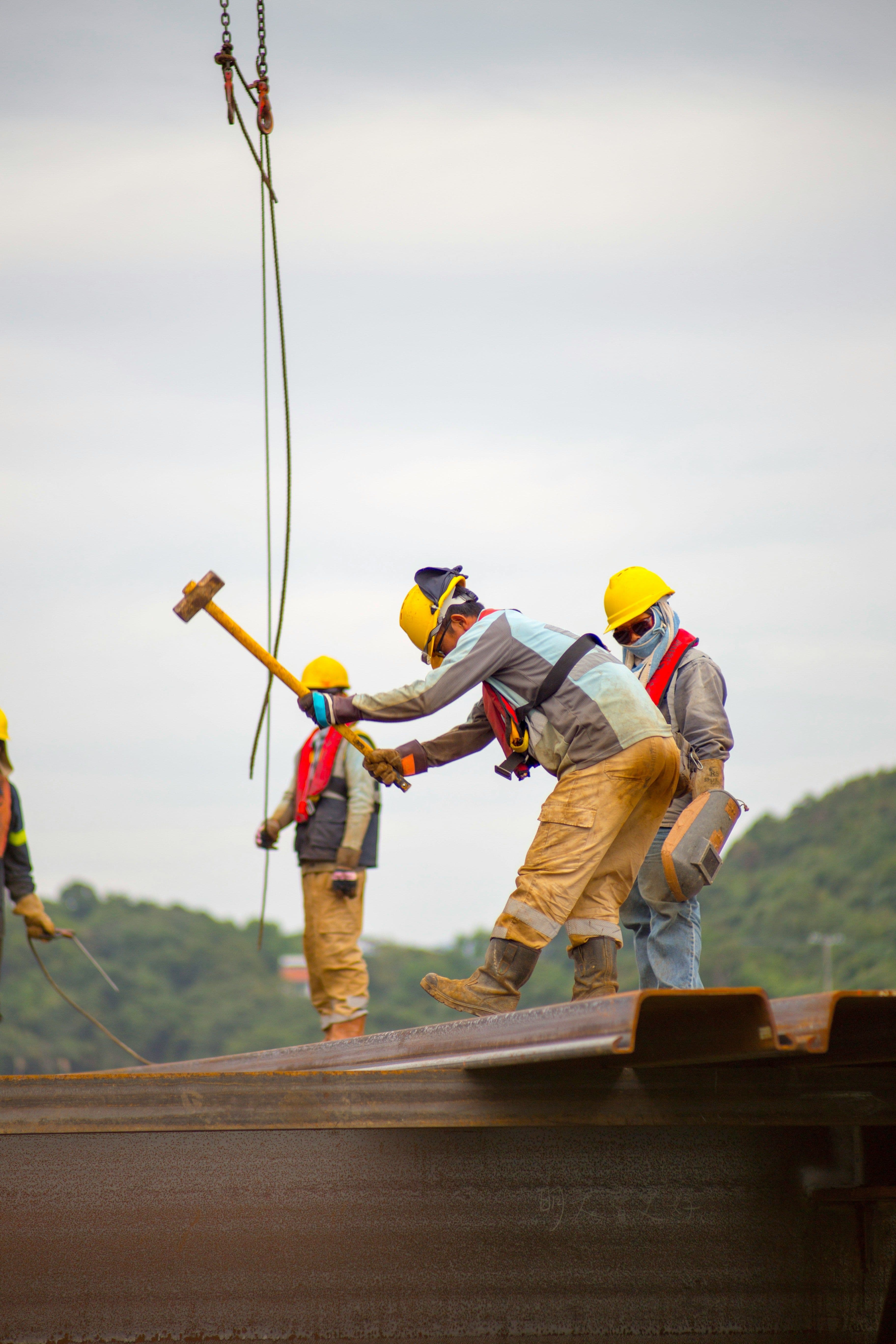 Construction worker hitting a piece of wood with a large hammer