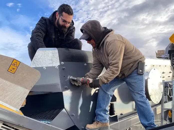 two guys setting up a 3-way screener making sure that it is well maintained