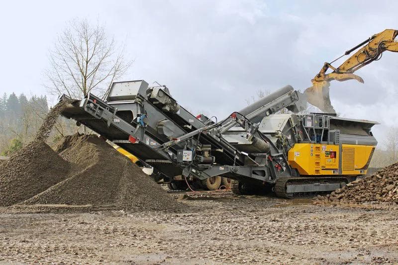 yellow rubble master 100GO! impact crusher crushing rock and being loaded by an excavator