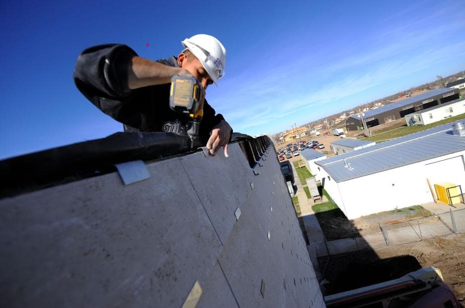 construction worker using an impactor gun to crew metal plates together