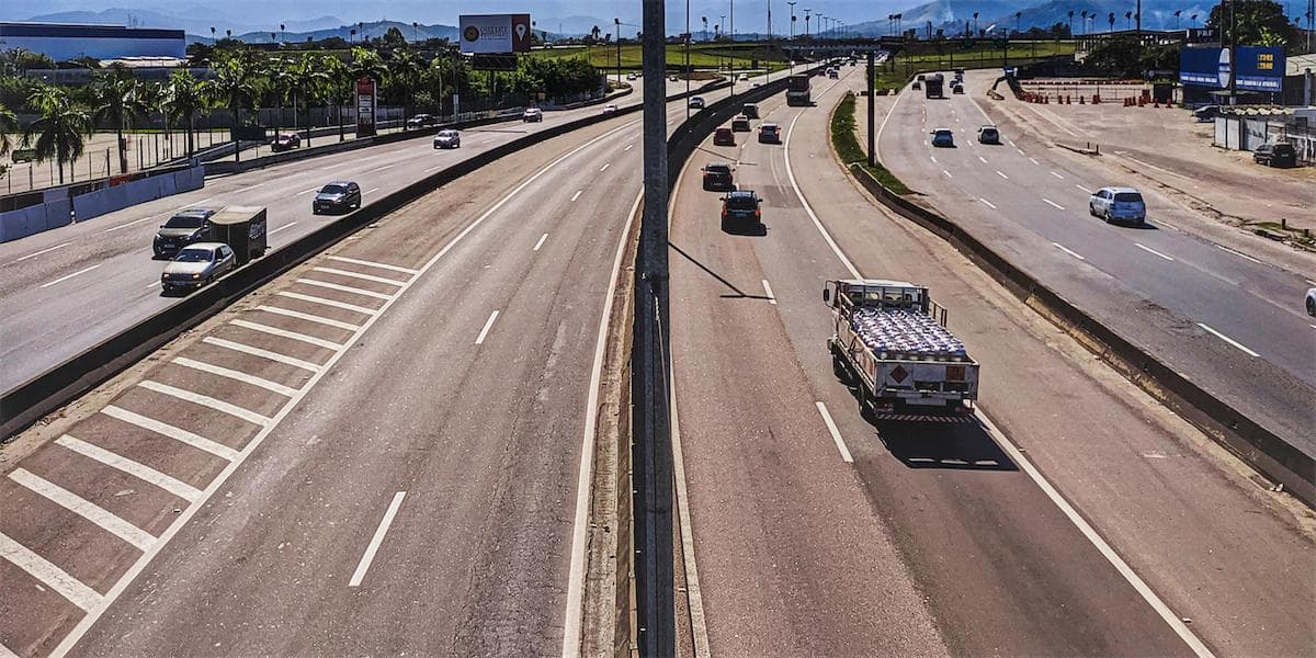 asphalt highway with cars, truck and trailers driving on both sides of the road. It is a busy highway
