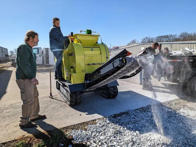 yellow ark 503 jaw crusher crushing on site with two customers. They are making a large pile of crushed concrete that is white