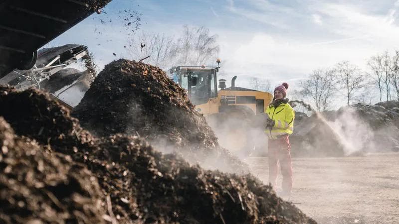 woman in personal protective equipment - ppe on site at a compost facility with a clipboard