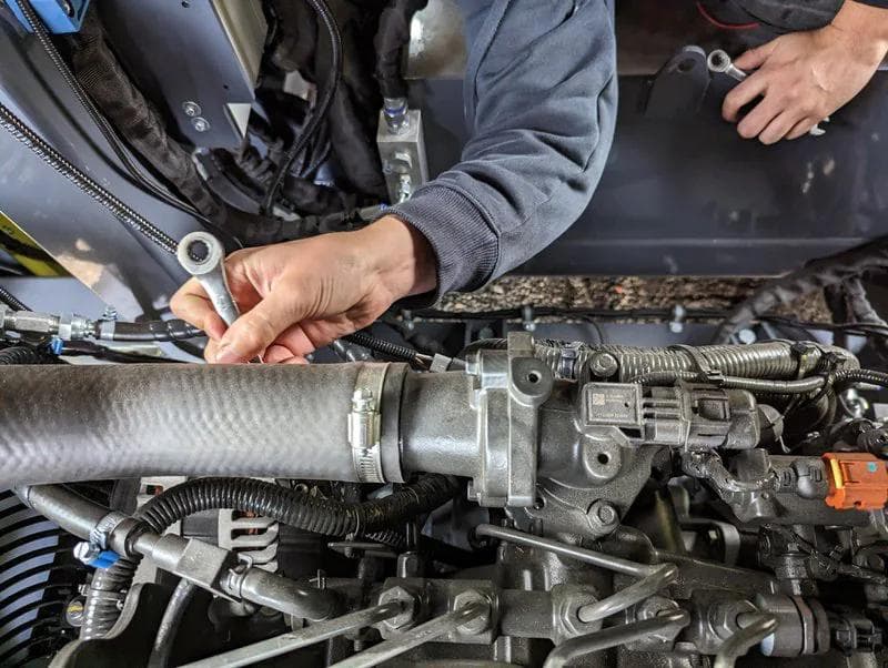 preventative maintenance being carried out on an engine with a wrench and a service tech in a blue jumper