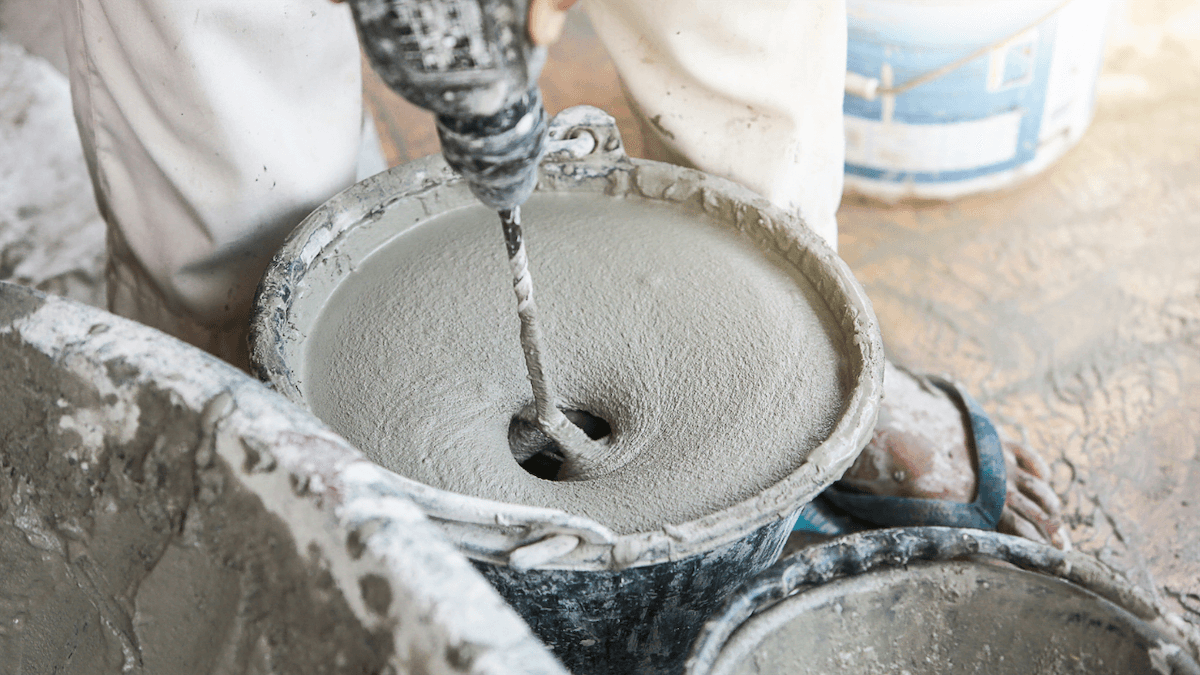 making concrete by hand using a drill to mix