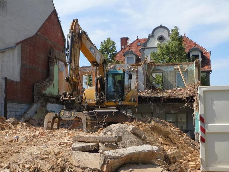excavator with a grabber helping to break down a residentail house