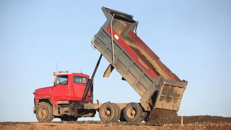 large red and balck dumptruck unloading compost onsite