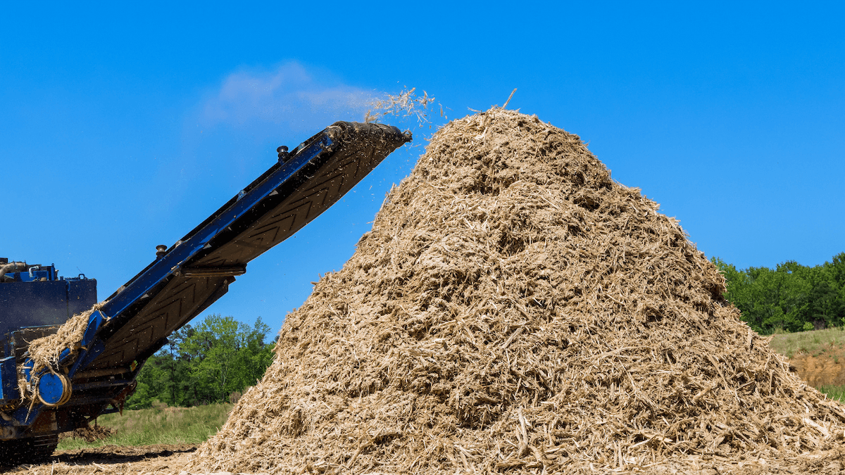 large shredder shredding wood into a huge pile