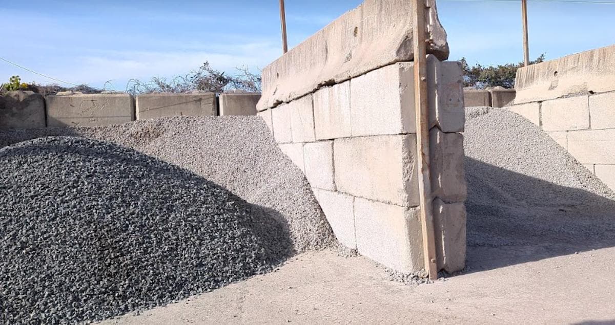 Crushed concrete in bins ready to be sold to customers. there are two bins made from concrete blocks that are stockpiled high with crushed concrete