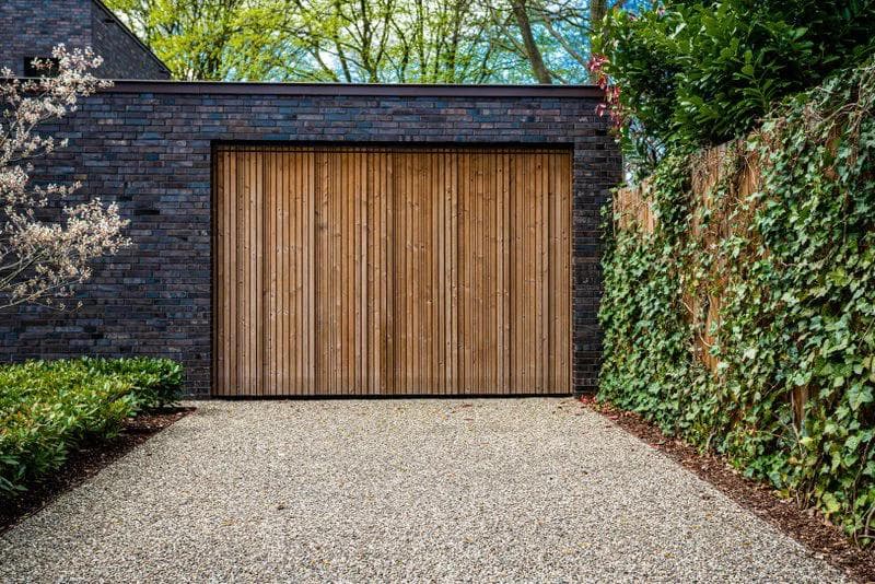 wide wood and stone garage door and crushed concrete driveway